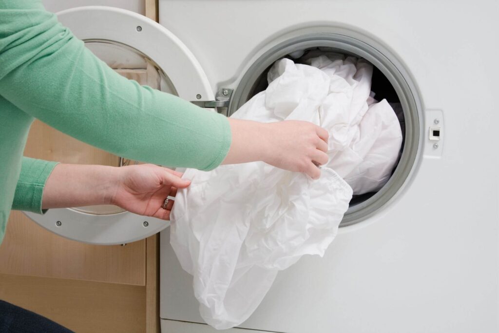 Cho ga giường, vỏ gối vào máy giặt và điều chỉnh lượng nước và chế độ làm sạch thích hợp