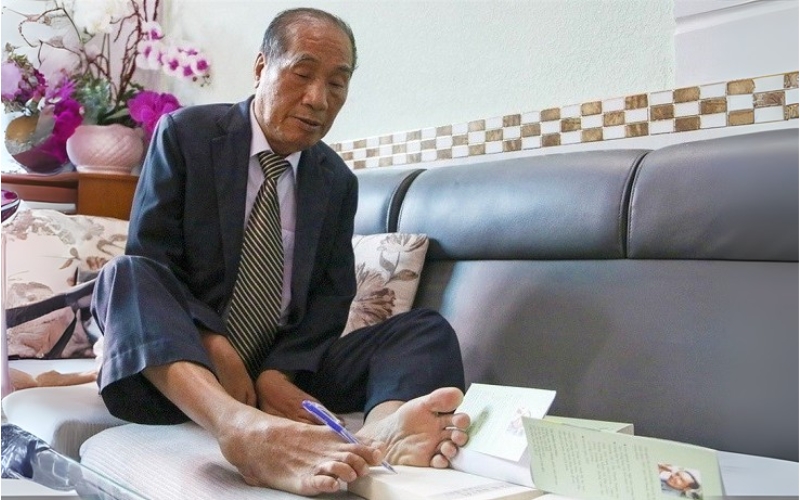 Chân dung nhà giáo ưu tú Nguyễn Ngọc Ký đang viết bằng chân, biểu tượng của ý chí kiên cường và khát vọng sống mãnh liệt